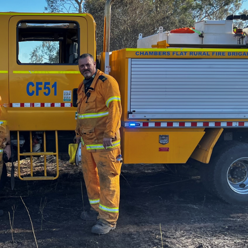 Geoff in his uniform standing in front of the Chambers Flat fire truck