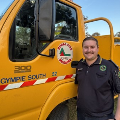Lewis in his uniform in from of a RFSQ yellow truck